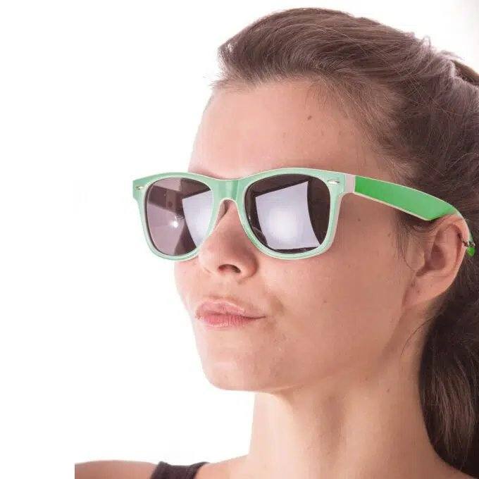 Femme portant des lunettes de soleil style wayfarer à monture vert fluo et verres foncés