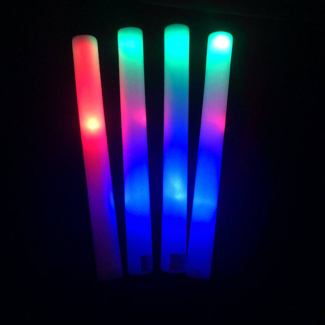Quatre bâtons mousse lumineux LED allumés en rouge, vert et bleu