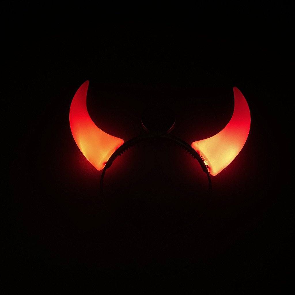 Serre-tête noir à grandes cornes de diable rouges allumées dans le noir