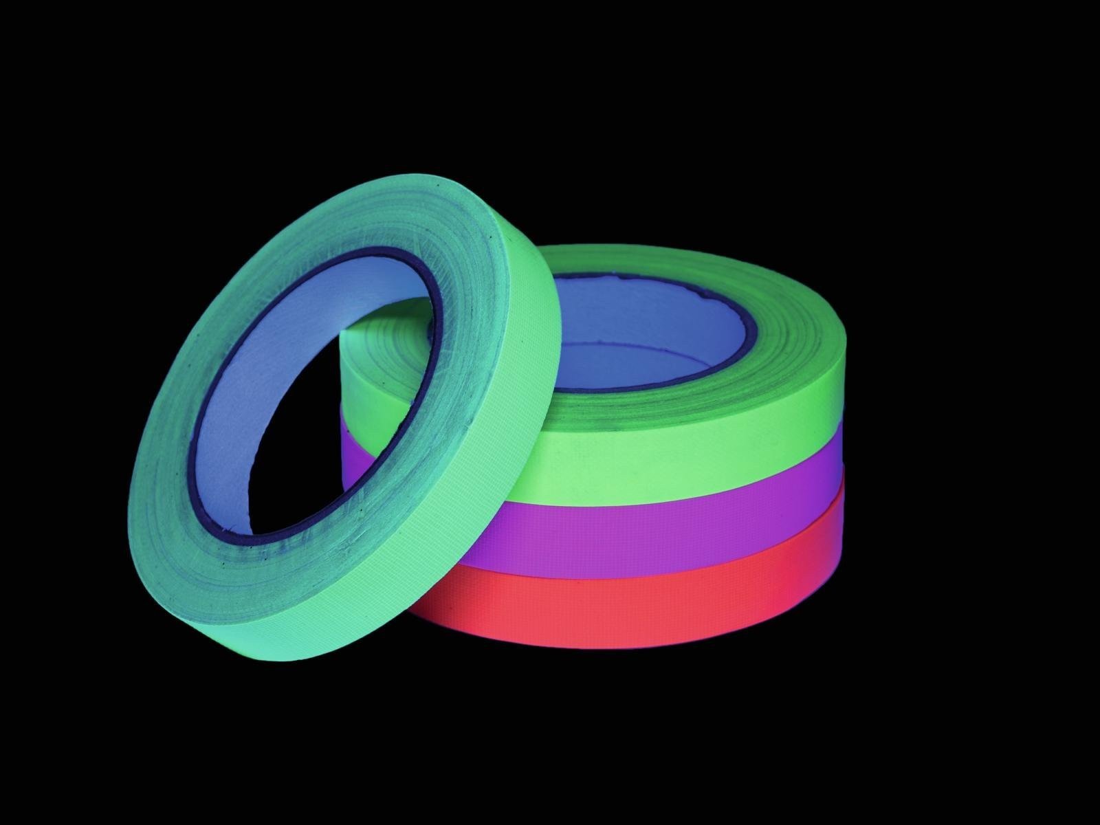 Rouleaux de ruban adhésif fluo vert, rose et orange sous lumière noire